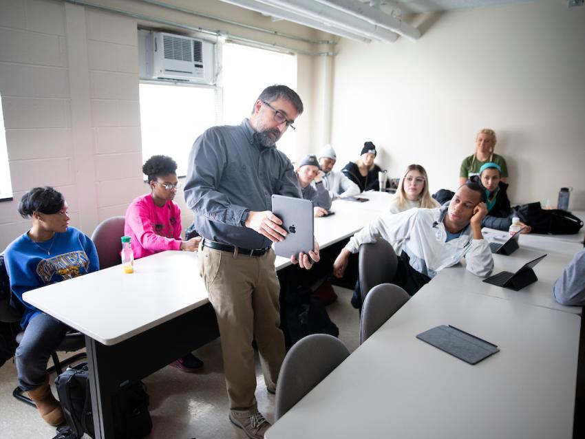 An instructor points to information on an iPad to a small class.